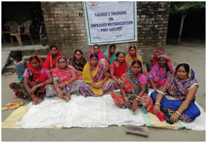 Women farmers seated for training beside grain spread on a sheet.