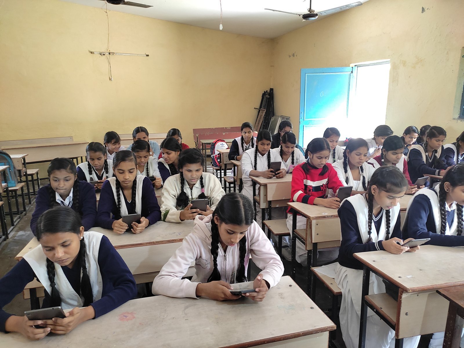 Schoolgirls use mobile devices during a digital classroom session.