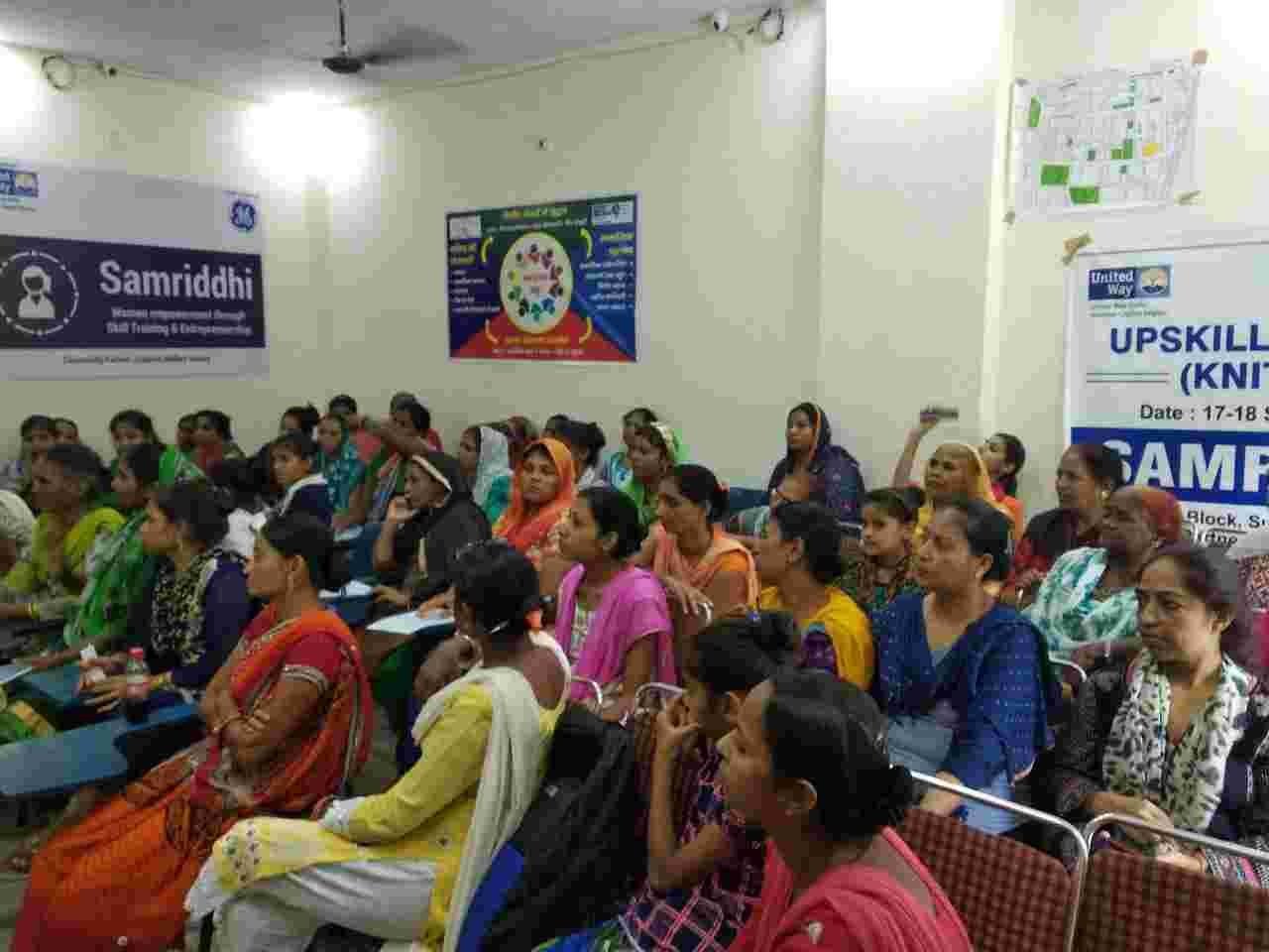 A room filled with women seated and listening during an upskilling session.