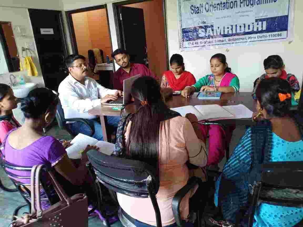 People seated around a table with notebooks during an orientation session.