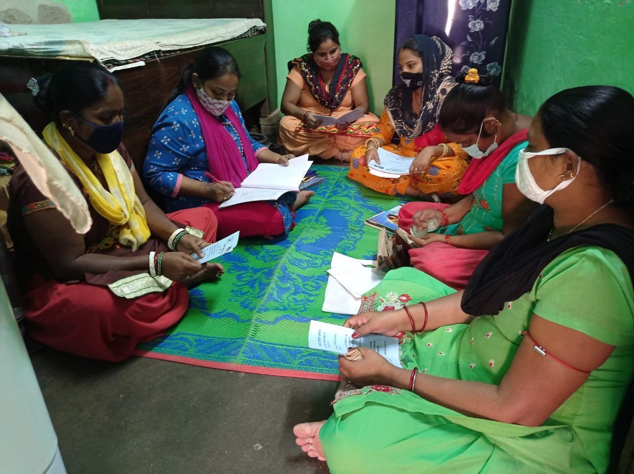Women seated together with forms and money during a self-help group meeting.