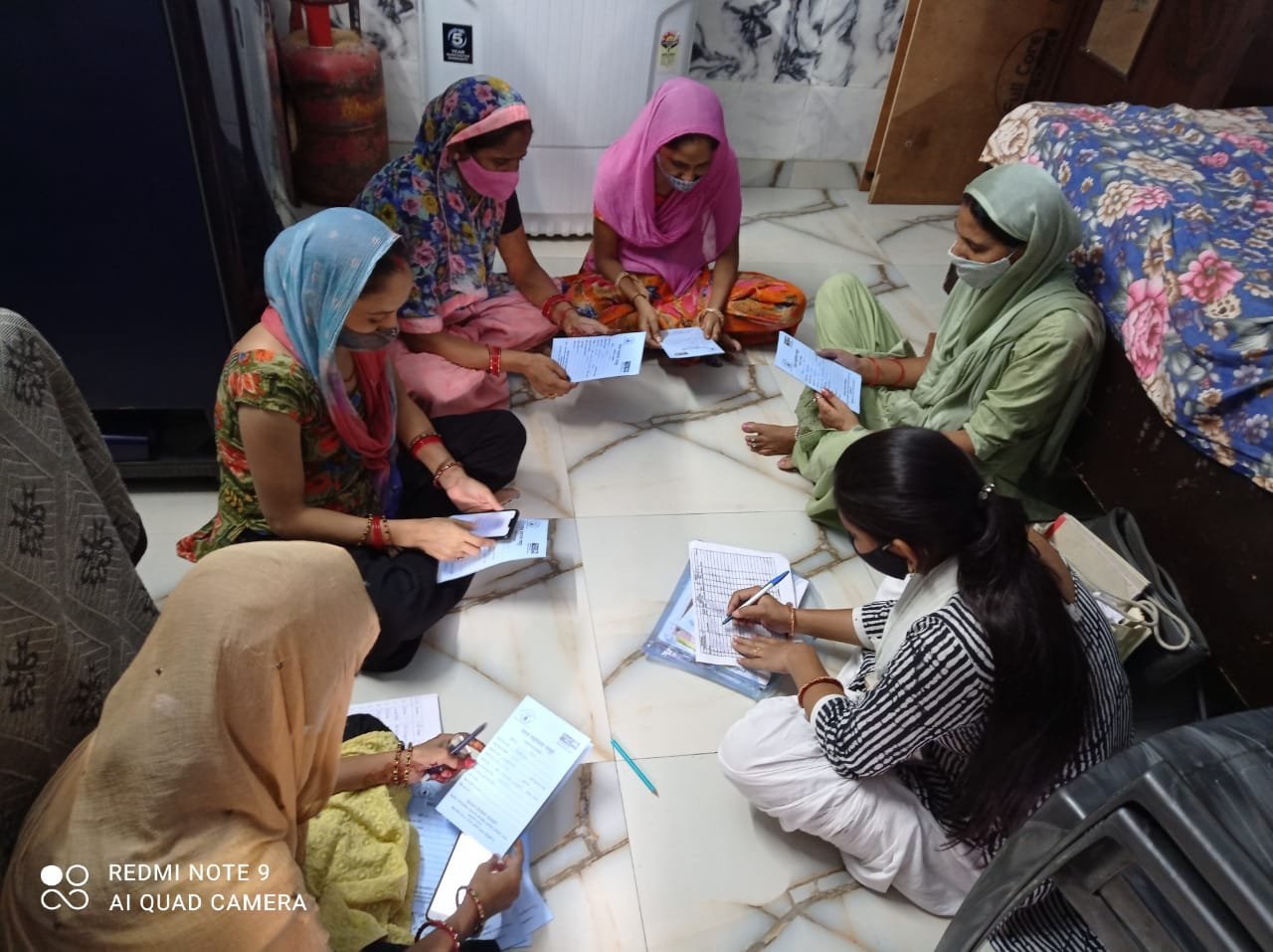 Women reviewing papers while one member writes in a register.