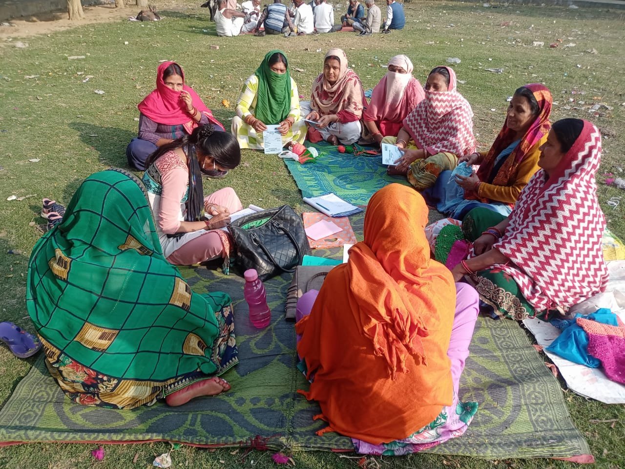 Women seated together outdoors during a self-help group meeting.